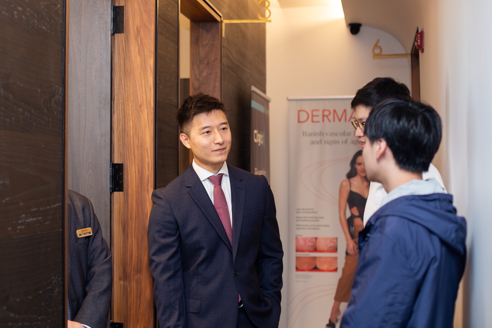 Haohui Yu in conversation with two attendees in a corridor of the facility