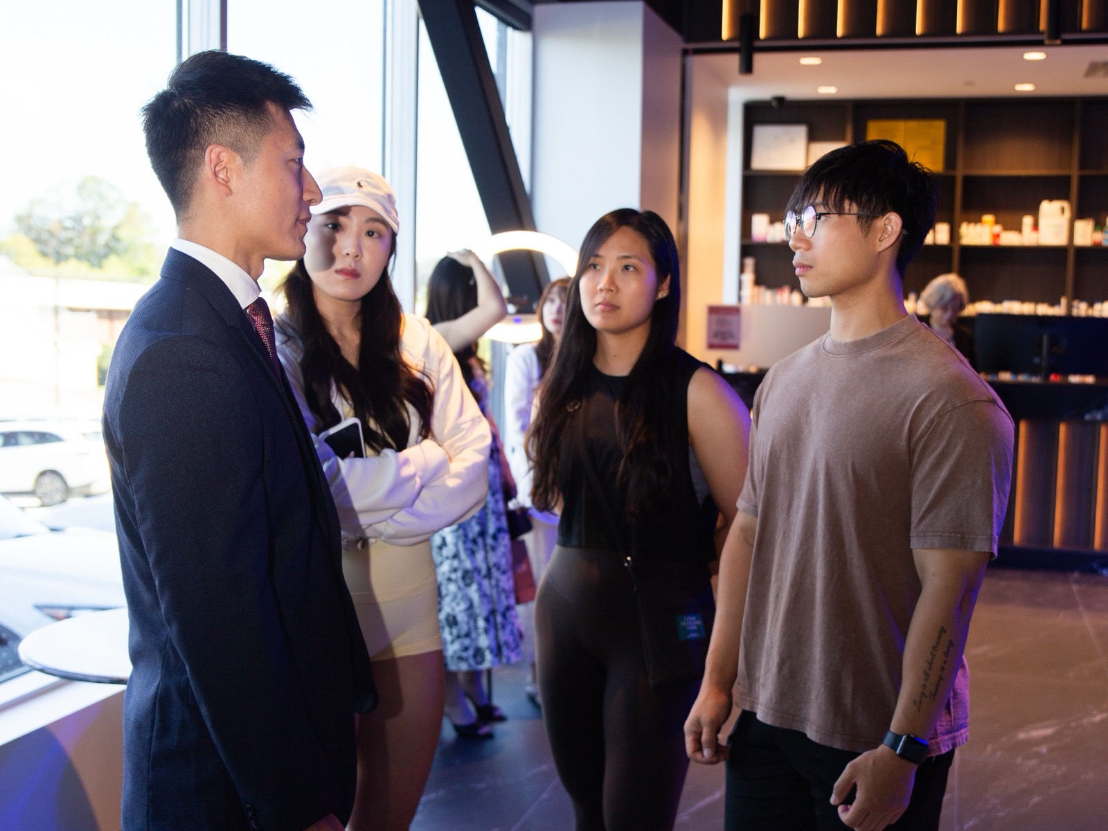 Haohui Yu, in a dark suit, standing in a clinic lounge listening to three young residents