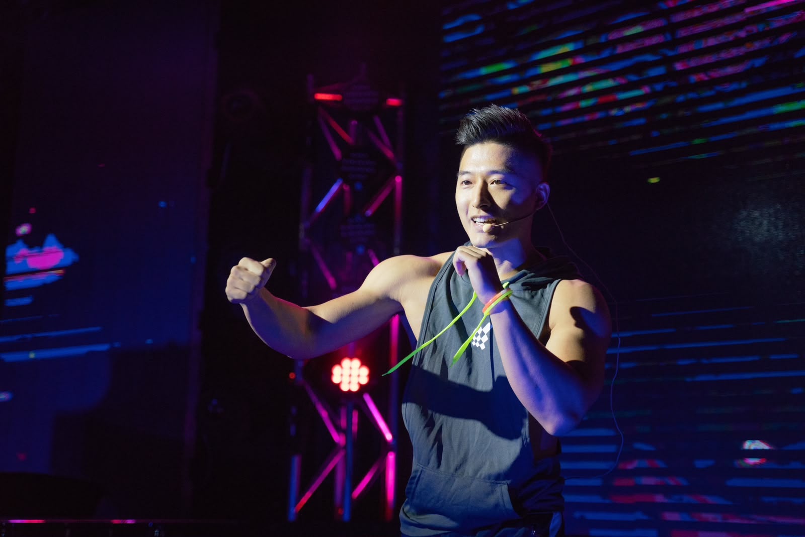 Haohui Yu leading a fitness class on a lit stage, mid-session